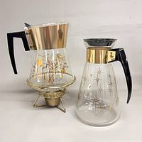 Both glass coffee carafes side by side with warmer stand attached to foliage carafe
