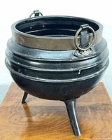 Full view of cauldron on stand showing legs and handles