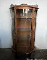 Front view of oak curved glass curio cabinet showing door, shelves, legs