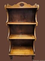 Front view showing three shelves, scalloped sides, turned legs