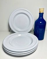 four stacked white side plates and blue oil decanter