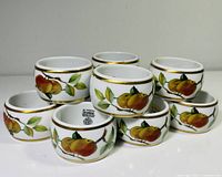 Stack of porcelain napkin rings showing fruit design and gold rims