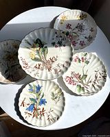 Top-down view of all five pieces showing floral designs and scalloped edges