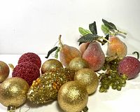 Group view of gold balls, red balls, beaded fruit ornaments, pinecone and grape cluster