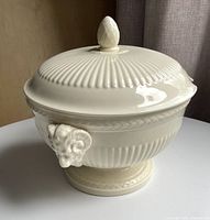 Full view of tureen with lid on, showing ribbed body, ram handle, footed base