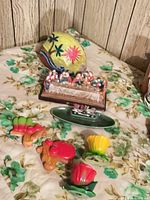 Group shot of all items: painted coconut, Last Supper figurine, die-cast truck on plate, chalkware vegetables, tulip shakers