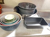 Nested coloured glass mixing bowls, stainless steel bowls, springform pan, loaf pan