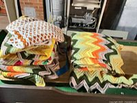 Stack of crocheted ripple afghans in various multicolor patterns