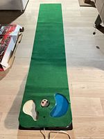 Full length view of green golf putting mat laid out on floor