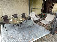 Group view of mosaic table, glass side table, three wicker chairs, two cushioned lounge chairs
