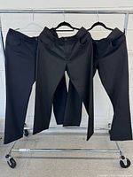 Three pairs of pants hanging on rack showing full fronts
