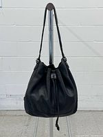 Front view of black leather Cole Haan drawstring bag on stand