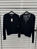 Both black cardigans on hangers showing overall style and color