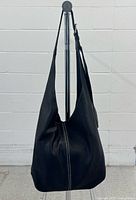 Full view of black leather Roots shoulder bag hanging on stand