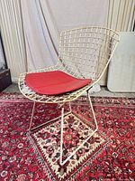 Front angled view of wire chair with red cushion