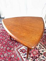 Triangular teak side table full view on rug