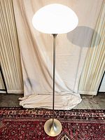 Full view of chrome floor lamp with illuminated frosted glass shade