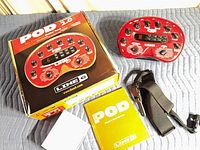 Top view of POD 2.0 unit, retail box, manual, strap, blank card