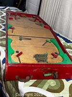 Angled close view of one end showing red frame, green crease, metal net and player rods