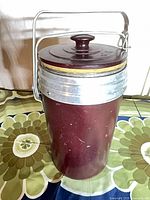 Front view of maroon Bakelite vacuum jug with lid and handle