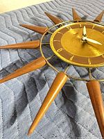 Angled close-up of brass dial, wood rays and white hands
