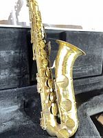 Full view of saxophone body inside case, shows missing neck