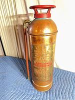 front view of copper fire extinguisher showing red handle, hose, and overall condition