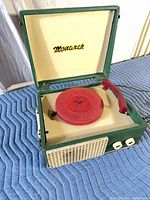 Record player open showing platter, tonearm, grille and knobs