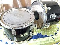 Rogers R360 tom upright with torn top head, Ludwig tom on side showing missing bottom head