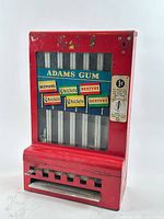 Front view of red Adams Gum vending machine showing glass panel with gum brand labels and coin mechanism