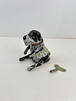 Side view of lithographed tin dog seated with key beside