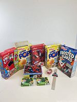 Group shot of cereal boxes, lunch box with figures, Jell-O boxes, ruler, electronic toy