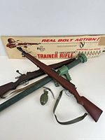 Overall lot showing two toy rifles, bazooka tube, grenade and original Trainer Rifle box