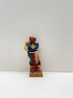 Front view of one Guatemalan cloth doll on wooden base carrying bundle