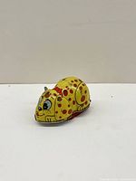 Side view of yellow spotty tin dog toy