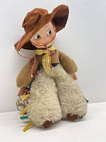 Front view of Merrythought cowboy doll showing hat, face, woolen chaps, ribbon fringe