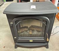 Front view showing arched glass door, faux logs and emblem
