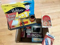 Open box showing Yahtzee, Triple Yahtzee score pads, Travel Yahtzee, Mille Bornes, Encore, Say Anything, dice cup