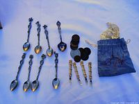 Full layout of 8 teaspoons, 4 forks, stack and loose coins, and blue pouch