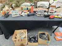 Overview of locomotives, buildings on table and two boxes of track