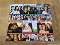 Front covers of all six Dawson's Creek season DVD box sets displayed on wood surface