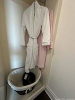 White and pink robes hanging, basket and travel pillow visible