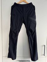 Front view of men’s black pinstripe pants hanging on hanger