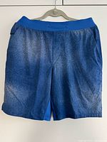 Full front view of blue swim shorts on hanger