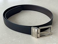 Full view of coiled black leather belt with buckle