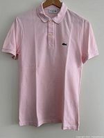 Front view of pale pink Lacoste polo shirt showing logo and collar