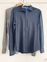 Front view of black shirt hung over green shirt