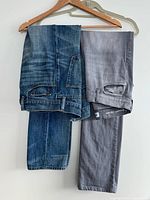 Gray and blue jeans draped over hanger