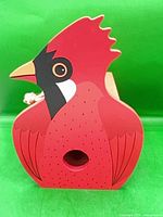 Front view of cardinal-shaped wooden birdhouse showing entrance hole and painted details