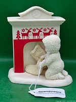 Front view of Snowbabies figurine with fireplace and knitted stocking